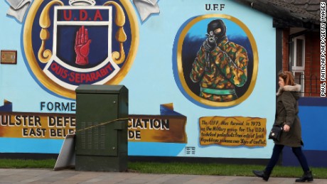 A woman walks past a loyalist mural, depicting an Ulster Freedom Fighter (UFF) in Belfast. 
