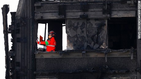 Emergency services crews work on the top floor of the charred remains of the Grenfell Tower.