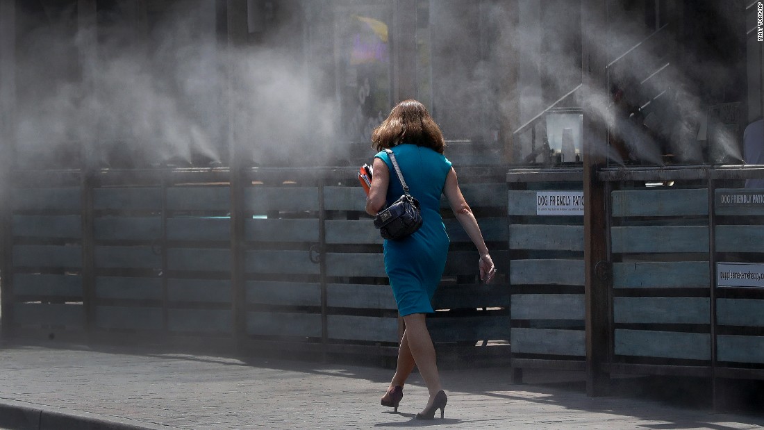 A woman walks through cooling mist in Tempe on June 19.