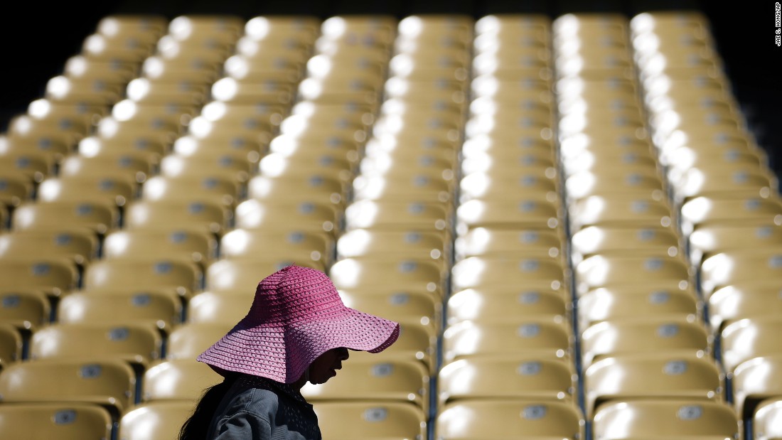 A worker wears a large hat, wet with water, while cleaning seats at Los Angeles Dodger Stadium on June 19.