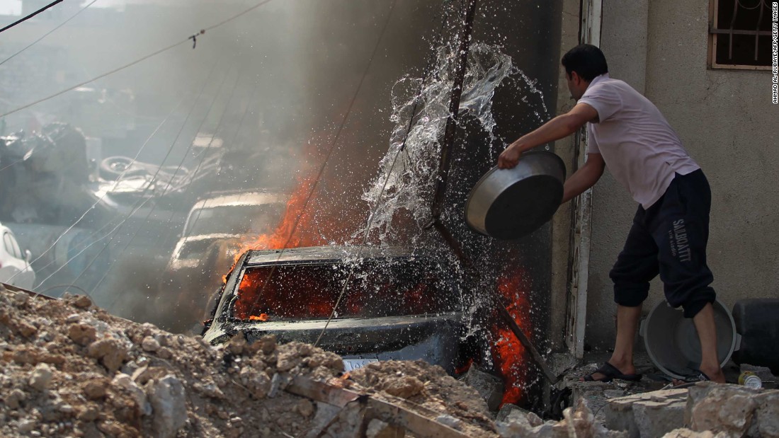 An Iraqi man tries to extinguish a burning car during fighting in Mosul&#39;s western Rifai neighborhood on Tuesday, May 16.