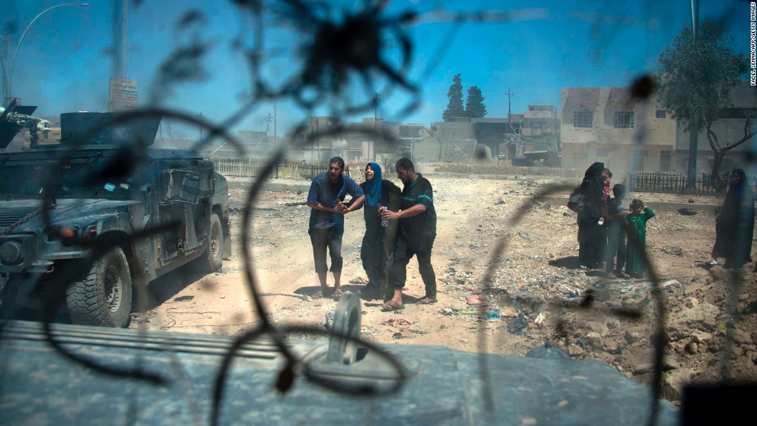 Displaced Iraqis make their way through rubble after evacuating their homes in a neighborhood of west Mosul on Wednesday, May 17.