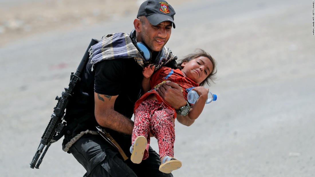 An Iraqi soldier helps transport a girl as residents flee their homes west of Mosul on Friday, May 26.