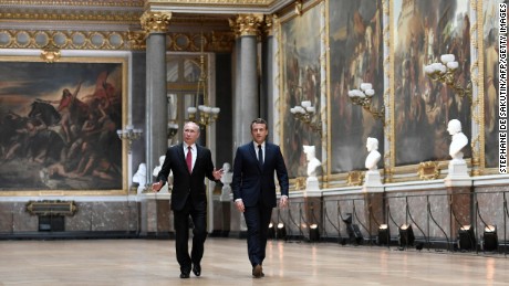 Russian President Vladimir Putin looks around as he walks alongside Macron in the Galerie des Batailles.
