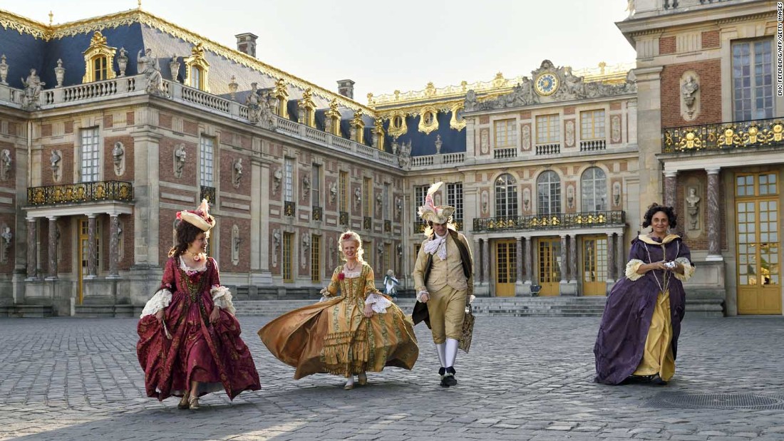 People dressed in period costumes walk across the courtyard at the Palace of Versailles.