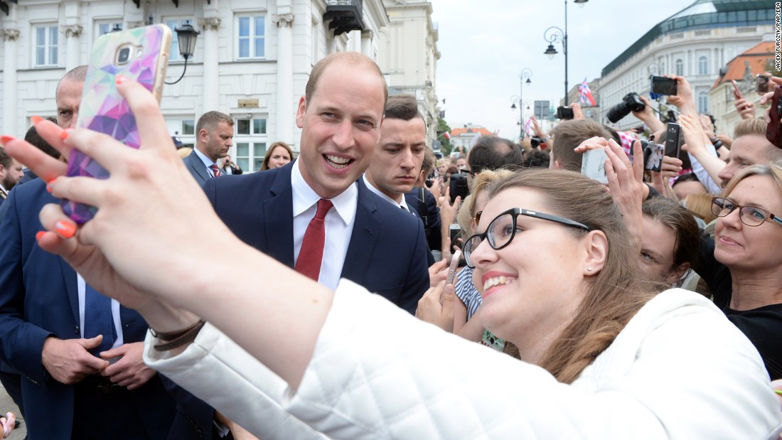 William poses for a selfie with a woman on July 17, as a crowd gathers outside the Presidential Palace in Warsaw, Poland, to greet the royals.
