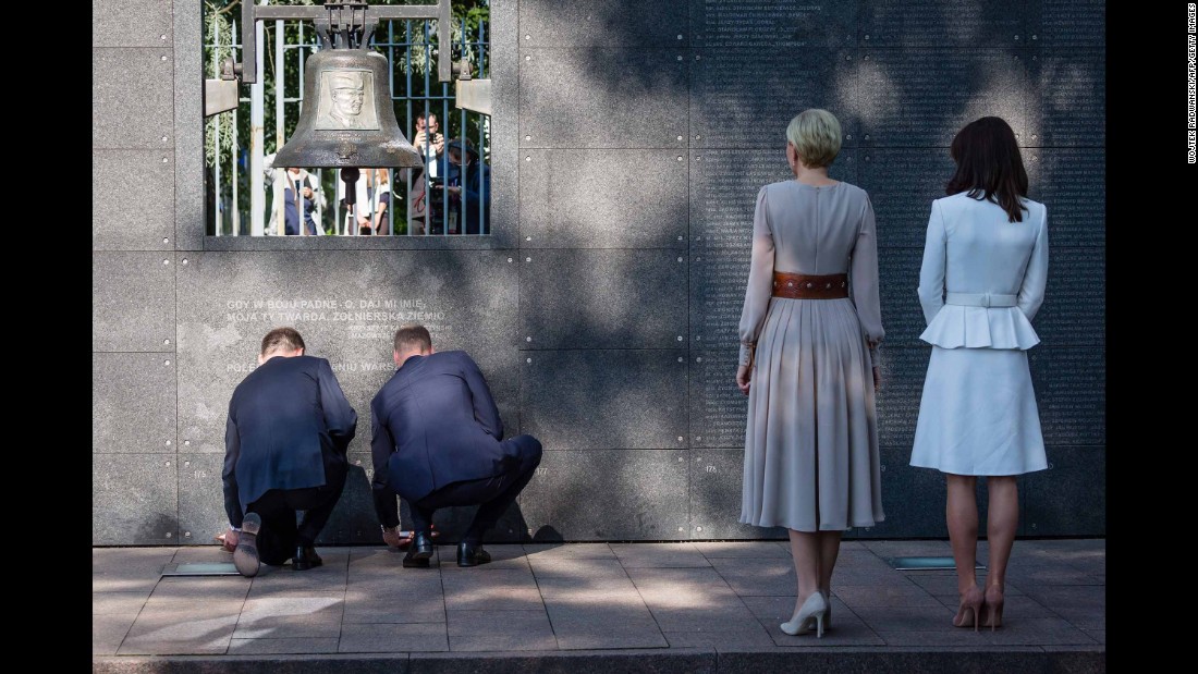 Duda, left, and William, kneel as they light candles during a visit to the Warsaw Uprising Museum while Poland&#39;s first lady, second from right, and Kate look on.