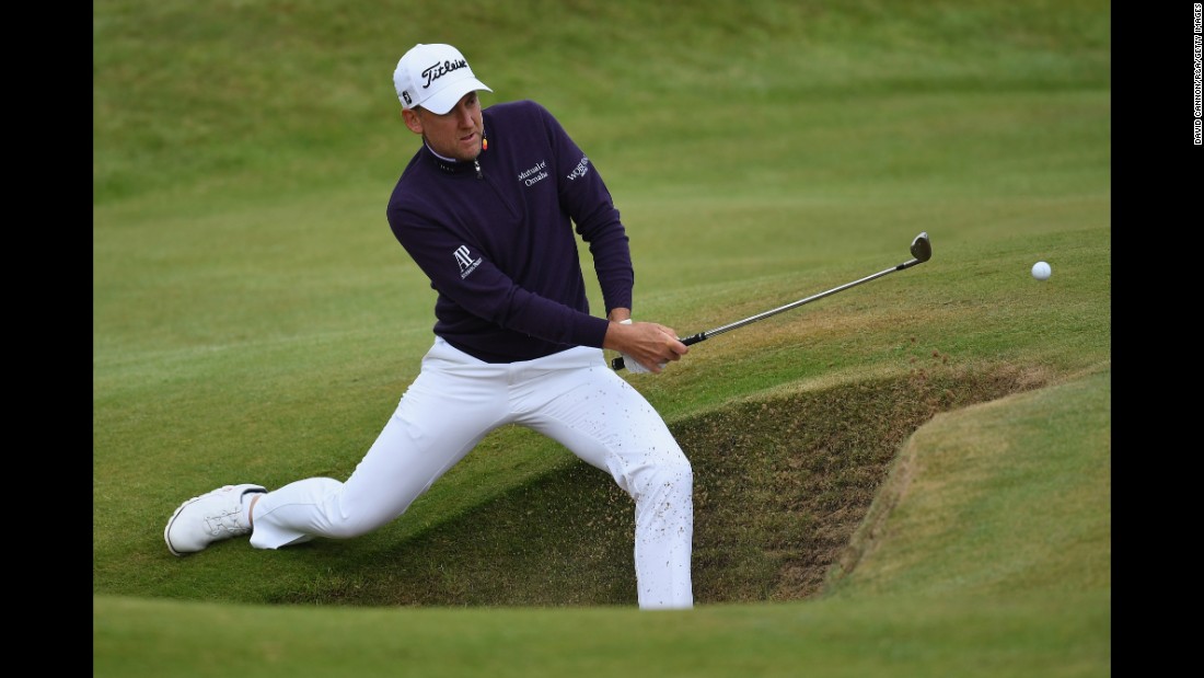 Ian Poulter of England plays out of a bunker on the seventh hole.  