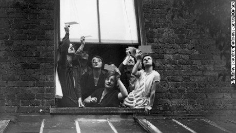 A group gathered in a window to view the total solar eclipse over London through smoked glass. 29th June 1927