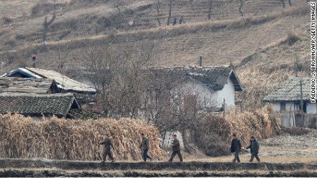 North Korean men walk amid a dry and barren landscape on the banks of the Yalu River in November 2010.