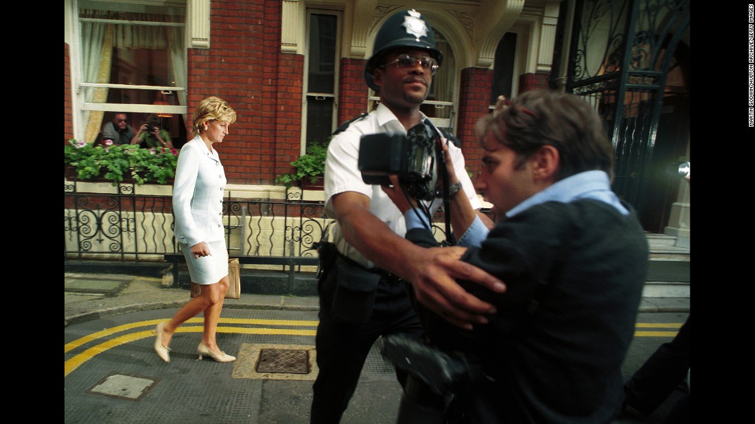 A police officer holds back a photographer as Diana walks by in July 1996. It had just been announced that Diana and Charles had divorced.