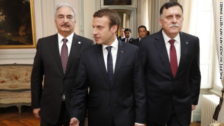 French President Emmanuel Macron (C) walks with Libyan Prime Minister Fayez al-Sarraj (R) and General Khalifa Haftar (L), commander in the Libyan National Army (LNA).