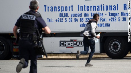 A police officer chases a youth suspected of being a migrant in a lorry park on the outskirts of Calais.
