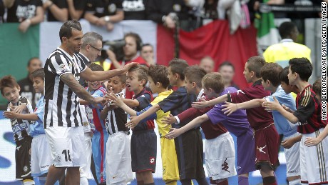 Juventus' Argentinian forward Carlos Tevez is welcomed by children wearing jerseys of the teams of the Italian championship before to receive the trophy of the Italian Serie A after their last football game of the season Juventus vs Cagliari on May 18, 2014 at the Juventus Stadium in Turin. Juventus won their third consecutive "scudetto". AFP PHOTO / MARCO BERTORELLO        (Photo credit should read MARCO BERTORELLO/AFP/Getty Images)