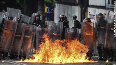 Members of the National Guard use their shields behind a fire during clashes with anti-government demonstrators in Caracas, on July 26, 2017. Venezuelans blocked off deserted streets Wednesday as a 48-hour opposition-led general strike aimed at thwarting embattled President Nicolas Maduro&#39;s controversial plans to rewrite the country&#39;s constitution got underway. /