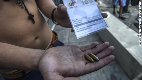 An anti-government activist shows an ID card and 9mm two 9mm bullets seized to a presumed security forces' infiltrator during a protest against the election of a Constituent Assembly proposed by Venezuelan President Nicolas Maduro, in Caracas on July 30, 2017.
Deadly violence erupted around the controversial vote, with a candidate to the all-powerful body being elected shot dead and troops firing weapons to clear protesters in Caracas and elsewhere. / AFP PHOTO / JUAN BARRETO        (Photo credit should read JUAN BARRETO/AFP/Getty Images)