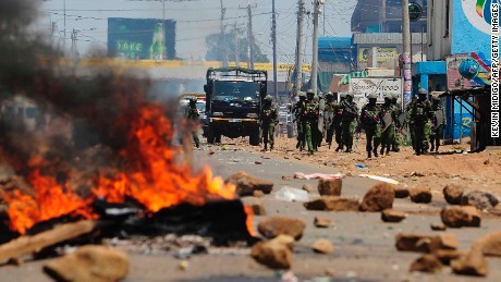 Kenyan security personnel walk towards burning barricades on a road in Kisumu on Wednesday.