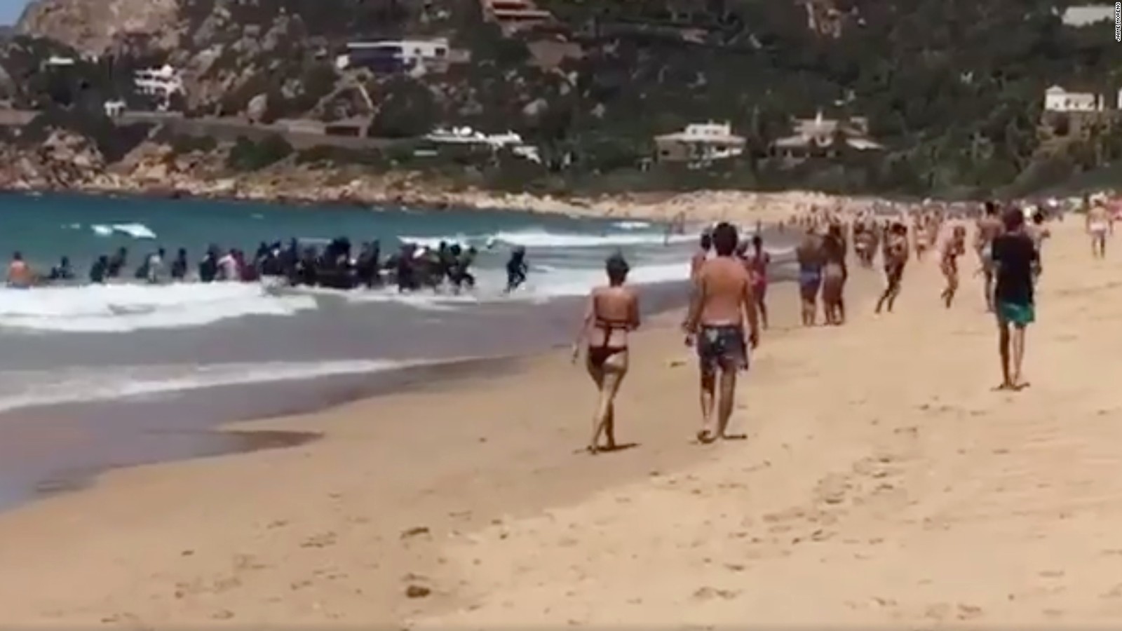 Image result for boat full of migrants lands on packed Spanish beach