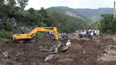 Heavy machinery removes debris as rescue personnel search for survivors and bodies of victims after a landslide along a highway in Northern India. 