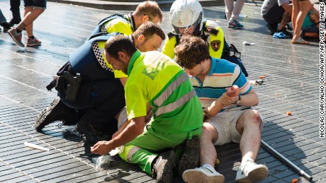 A person is helped by Spanish policemen and two men after a van ploughed into the crowd, killing at least 13 people and injuring around 100 others on the Rambla in Barcelona on August 17, 2017.
A driver deliberately rammed a van into a crowd on Barcelona&#39;s most popular street on August 17, 2017 killing at least 13 people before fleeing to a nearby bar, police said. 
Officers in Spain&#39;s second-largest city said the ramming on Las Ramblas was a &quot;terrorist attack&quot;. The driver of a van that mowed into a packed street in Barcelona is still on the run, Spanish police said. / AFP PHOTO / Nicolas CARVALHO OCHOA        (Photo credit should read NICOLAS CARVALHO OCHOA/AFP/Getty Images)