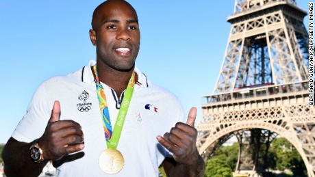 French judoka Teddy Riner poses with his gold medal in front of the Eiffel tower on August 23, 2016 in Paris. 
France&#39;s Olympic team landed in Paris on August 23, 2016 after winning 42 medals in Rio, including 10 golds, a postwar record for the overall medal count. / AFP / Bertrand GUAY        (Photo credit should read BERTRAND GUAY/AFP/Getty Images)