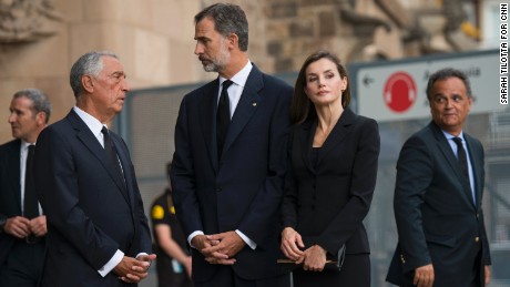 Spain&#39;s King Felipe VI, center, speaks to officials before the mass, while his wife Queen Letizia looks on at the crowd outside.