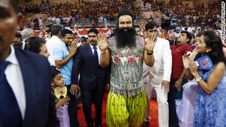 FILE- In this Oct. 5, 2016 file photo, Indian spiritual guru who calls himself Saint Dr. Gurmeet Ram Rahim Singh Ji Insan, center, greets followers as he arrives for a press conference ahead of the release of his new movie &quot;MSG, The Warrior Lion Heart,&quot; in New Delhi, India. Several cities in north India were under a security lock down Thursday ahead of a verdict in a rape trial involving a controversial and hugely popular spiritual leader. (AP Photo/Tsering Topgyal, File)