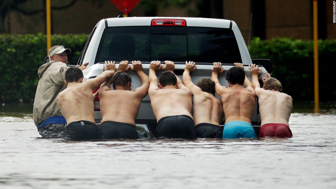 People push a stalled pickup through a flooded street in Houston.