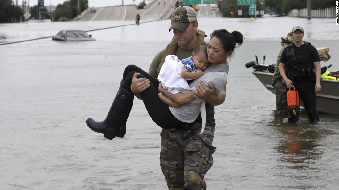 Houston police officer Daryl Hudeck carries Catherine Pham and her 13-month-old son, Aiden, after rescuing them from floodwaters.