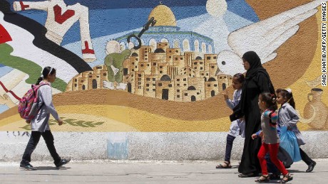 Palestinians walk past a mural in Gaza in 2014 featuring Handala, Naji al-Ali&#39;s most famous character, holding the key to the city of Jerusalem.