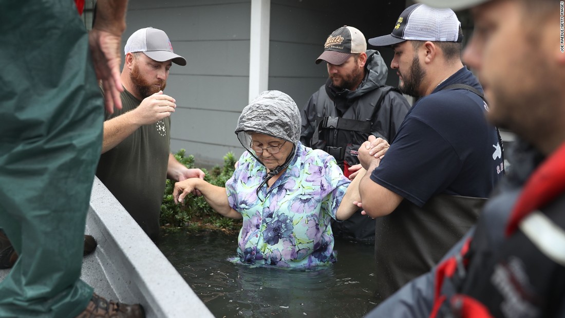 Volunteer rescue workers help a woman from her flooded home in Port Arthur, Texas.