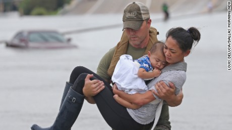 Houston SWAT officer Daryl Hudeck carries Catherine Pham and her son 13-month-old son Aidan to safety after they were rescued via boat from the flooding on Interstate 610 south in Houston on Sunday, August 27, 2017. (Louis DeLuca/The Dallas Morning News)