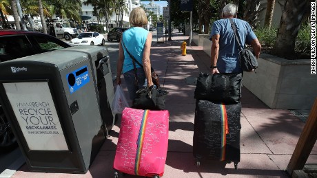 Tourist Bjorg Aasen and Arne Forsmo walk to catch a shuttle to a shelter as Miami Beach announced a mandatory evacuation.