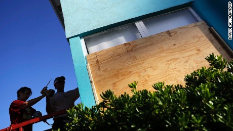 Paulita Kundid, left, and her brother Mike board up their apartment building on Friday in Daytona Beach.