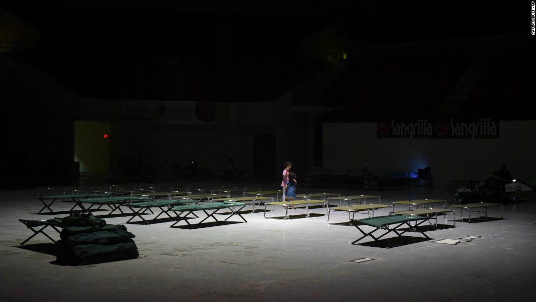 Two girls play on cots at the Humacao Arena.