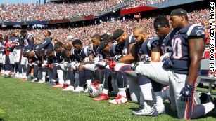 The words 'End Racism' are seen painted in an end zone during an NFL  football game