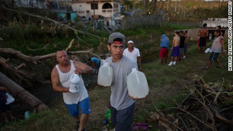 People carry water in bottles retrieved from a canal this week in Toa Alta, Puerto Rico.