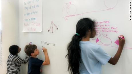 Children independently problem solve on walls made of whiteboards. 