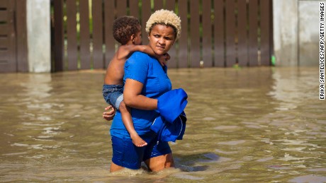 Local residents wade through the flooded streets of Arenoso, northeastern Dominican Republic, on September 24, 2017 after the passage of Hurricane Maria. 
The storm is blamed for 33 deaths, many of them on the tiny and poor island of Dominica and 13 in Puerto Rico. / AFP PHOTO / Erika SANTELICES        (Photo credit should read ERIKA SANTELICES/AFP/Getty Images)