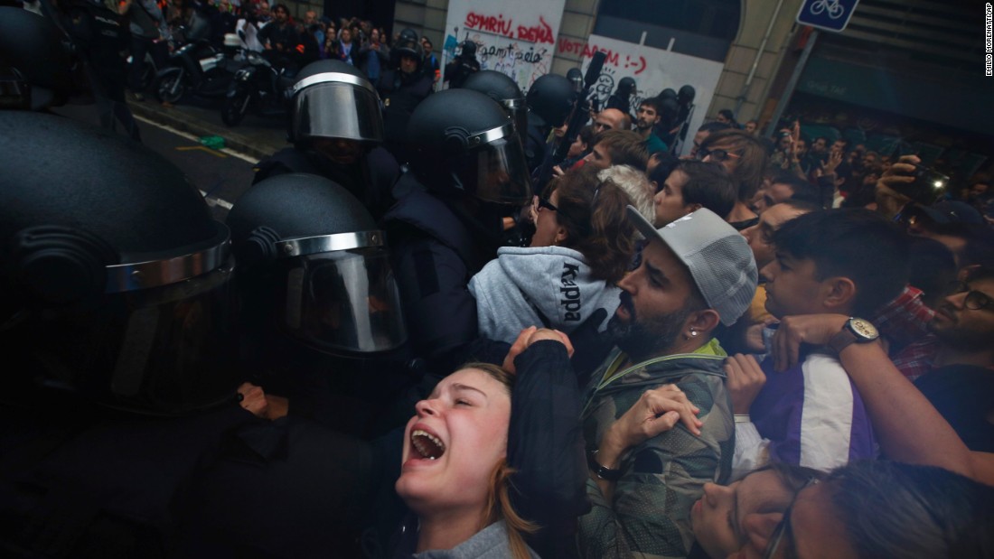 People clash with Spanish National Police outside the Ramon Llull school, designated as a polling station by the Catalan government in Barcelona, Spain, early Sunday, October 1. Catalan pro-referendum supporters vowed to ignore a police ultimatum to leave the schools they are occupying to use in a vote seeking independence from Spain.