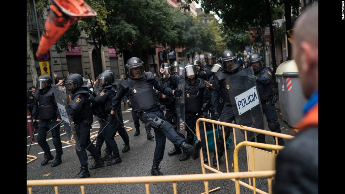 Spanish riot police remove fences thrown at them as they try to prevent people from voting in Barcelona, Spain, on Sunday, October 1. 