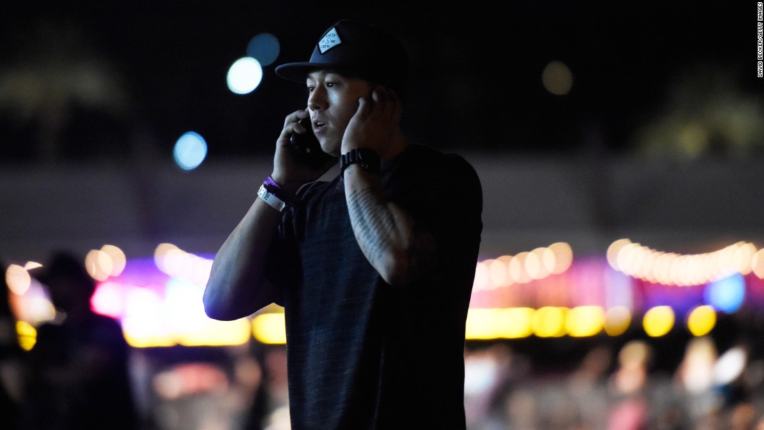 A man makes a phone call as people run from the festival grounds.