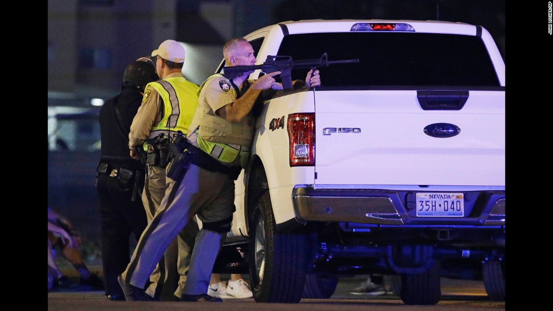 A police officer takes position behind a truck.