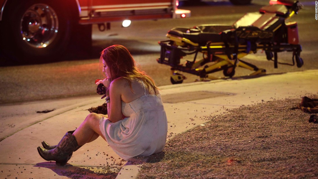 A woman sits on a curb at the scene of the shooting.