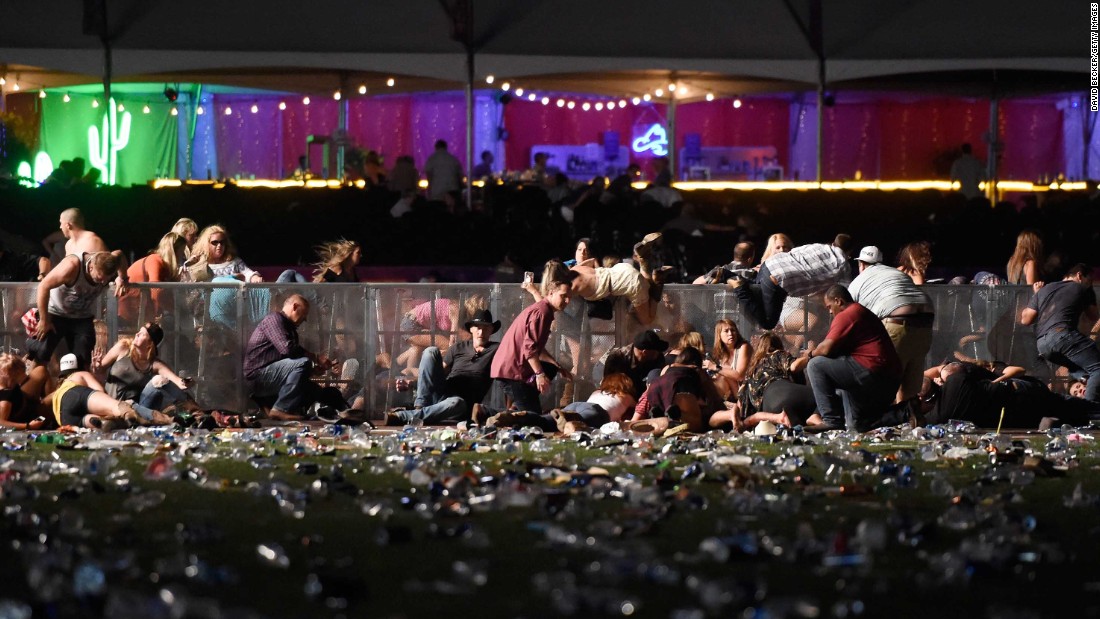 Concertgoers dive over a fence to take cover from gunfire on Sunday night.