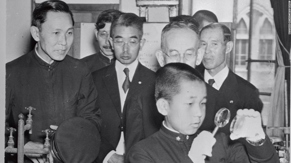 Akihito, 14, uses a magnifying glass at the Peers School in Tokyo. At about the age of 5, Akihito was separated from his parents, in accordance with Japanese custom at the time, and raised and educated by chamberlains and tutors.