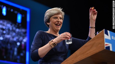 Britain&#39;s Prime Minister Theresa May holds up a throat lozenge given to her by Britain&#39;s Chancellor  Philip Hammond .