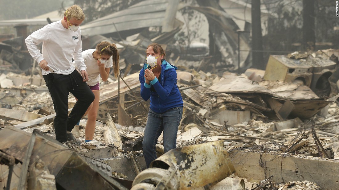 Mary Caughey, center in blue, reacts after finding her wedding ring in the remains of her home in Kenwood on October 10. 