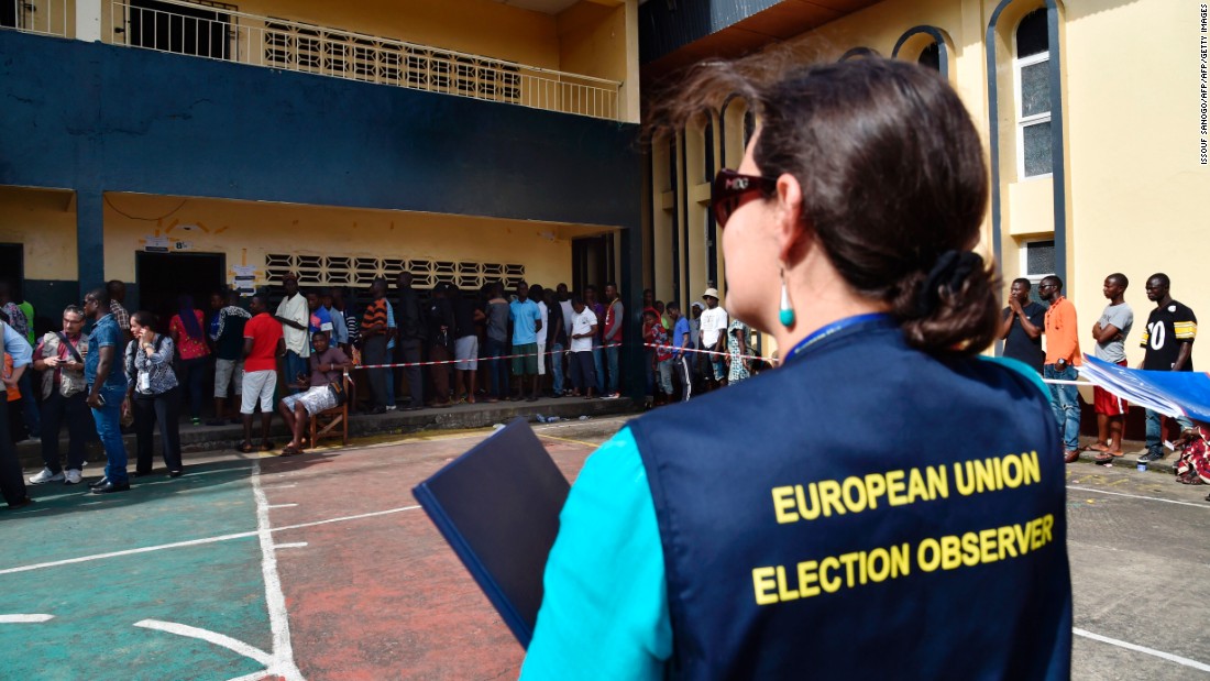 A European Union election observer stands near voters queuing at a polling station in Monrovia. &lt;br /&gt;Credit: Getty images