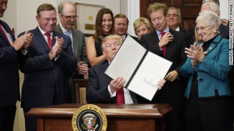 US President Donald Trump shows an executive order which he just signed on health insurance on October 12, 2017 in the Roosevelt Room of the White House in Washington, DC. / AFP PHOTO / MANDEL NGAN        (Photo credit should read MANDEL NGAN/AFP/Getty Images)